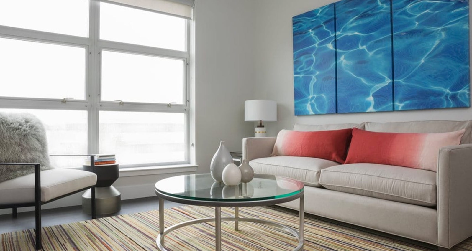 A staged living room with a glass coffee table and a corner of window