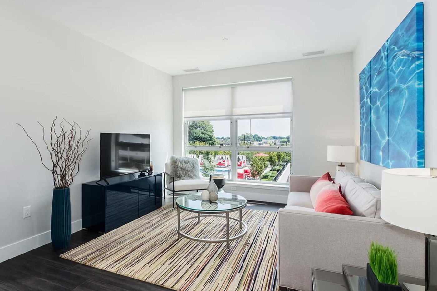 A living area with a television and a view onto the pool deck
